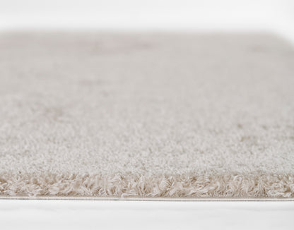 Cream beige shag rug with long plush pile and soft fringe edge, neutral living room rug.