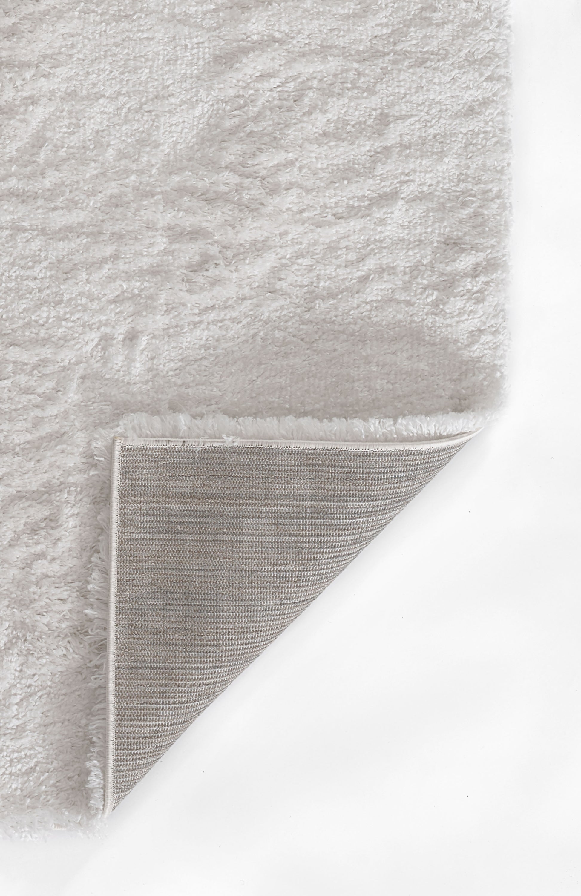 Cream shag rug with plush pile; folded corner reveals light woven underside; rectangular, cozy home decor.