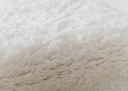 Cream white shag rug close-up, ultra-soft long fibers, plush texture, modern cozy decor accent.