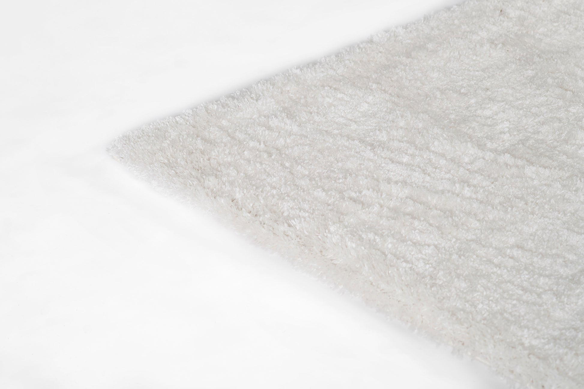 Cream shag rug with fluffy pile on white surface; rectangular, cozy home decor accent.