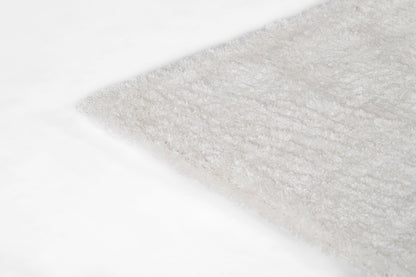 Ivory shag rug corner with fluffy pile, soft plush texture.