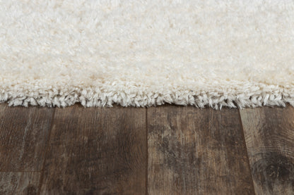 Cream white shag rug with fringe edge on dark brown wood flooring