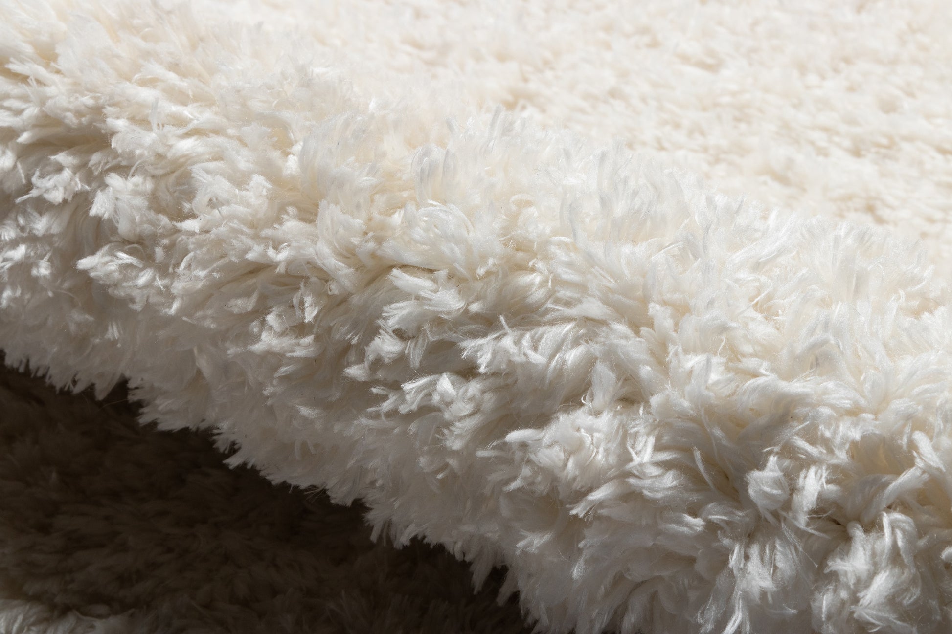 Cream-white shag faux fur rug with long plush fibers, soft cozy decorative throw.