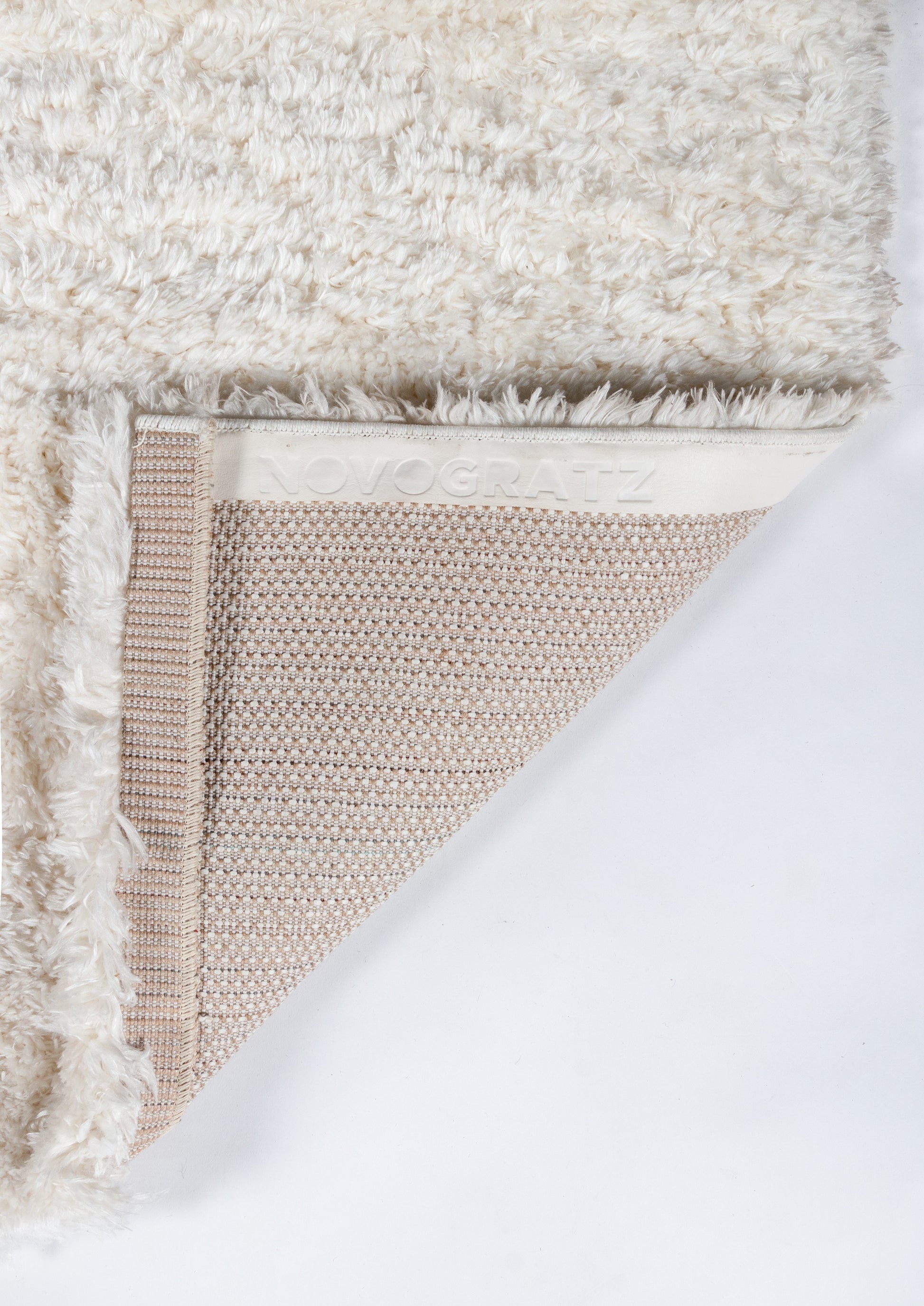 Cream fluffy shag rug with beige woven backing and a white embossed NOVOGRATZ band along the edge.