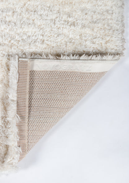 Cream shag rug with fluffy pile, beige woven backing and elastic edge, Novogratz branding.