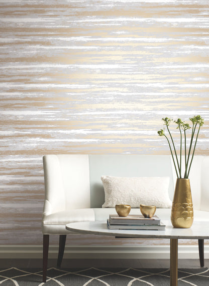 White sofa with pale blue backrest, textured pillow, marble coffee table, vase with stems, gold bowls, grey and gold striped wallpaper backdrop