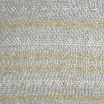 Grey woven fabric on an outdoor lumbar pillow featuring horizontal bands of white floral dots and yellow triangle motifs; geometric.