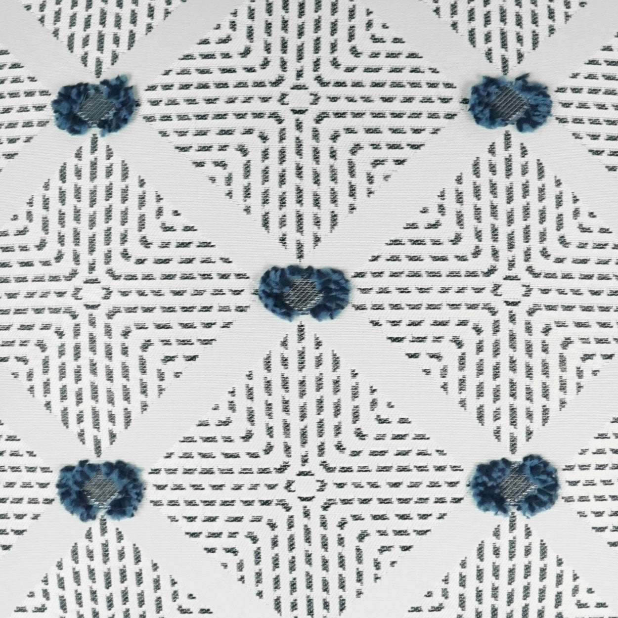 Outdoor lumbar pillow with white fabric, gray dash lattice pattern & blue embroidered flower clusters at diamond intersections; 12" x 24