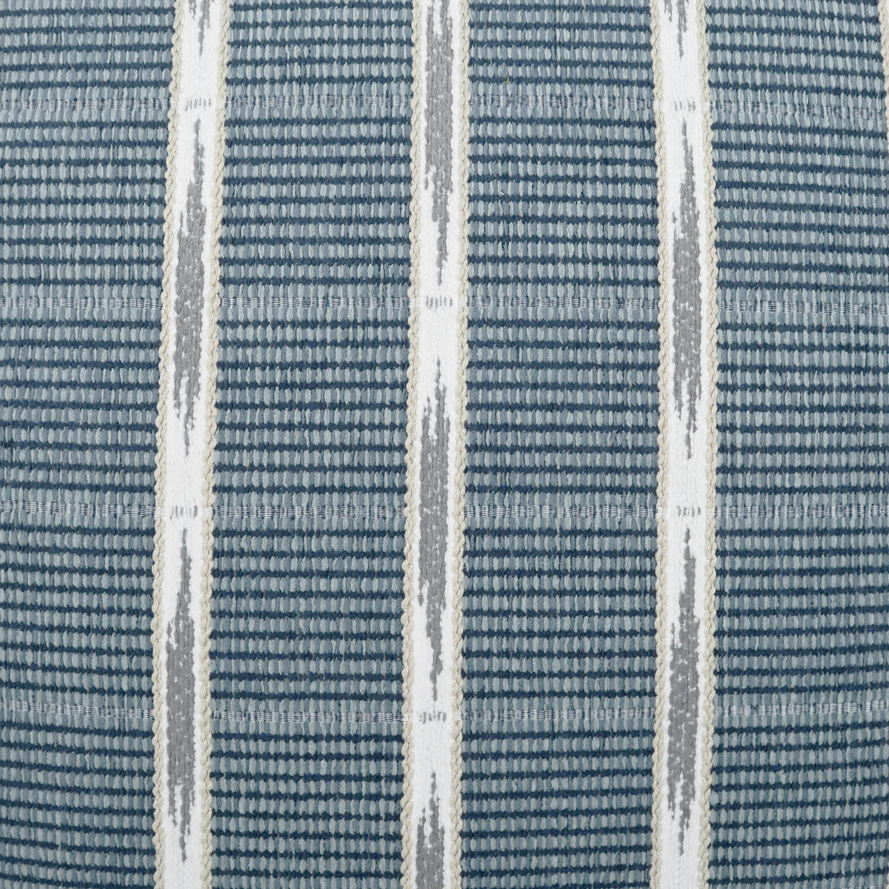 Blue woven fabric with white vertical stripes and gray diamond accents, close-up of an outdoor lumbar pillow plaid check