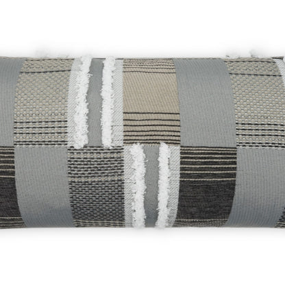 Patchwork upholstery fabric roll in gray, beige, and brown tones with woven stripes and white fringe.