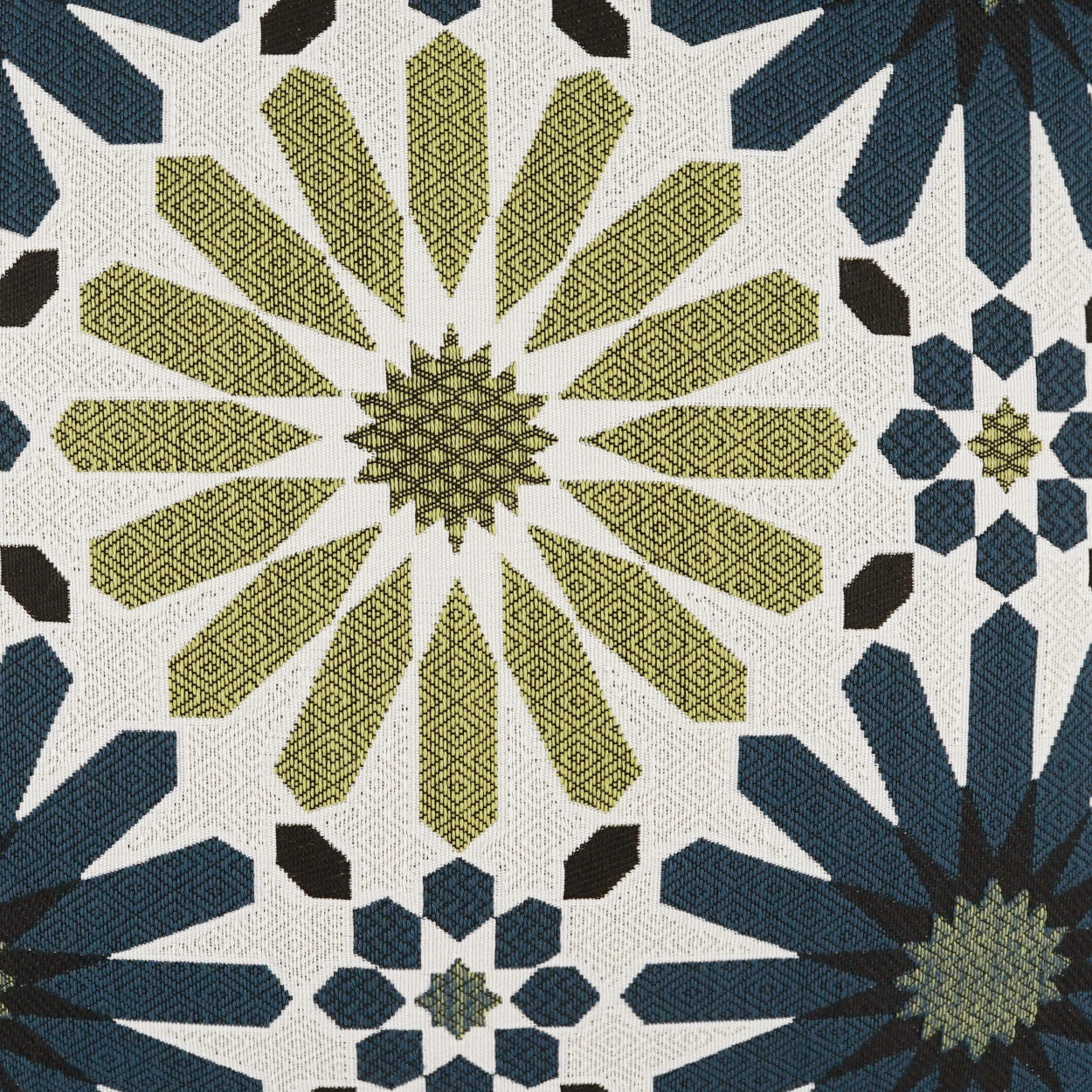 Geometric quilt woven fabric with olive-yellow starburst panels and navy blue star motifs on cream background.