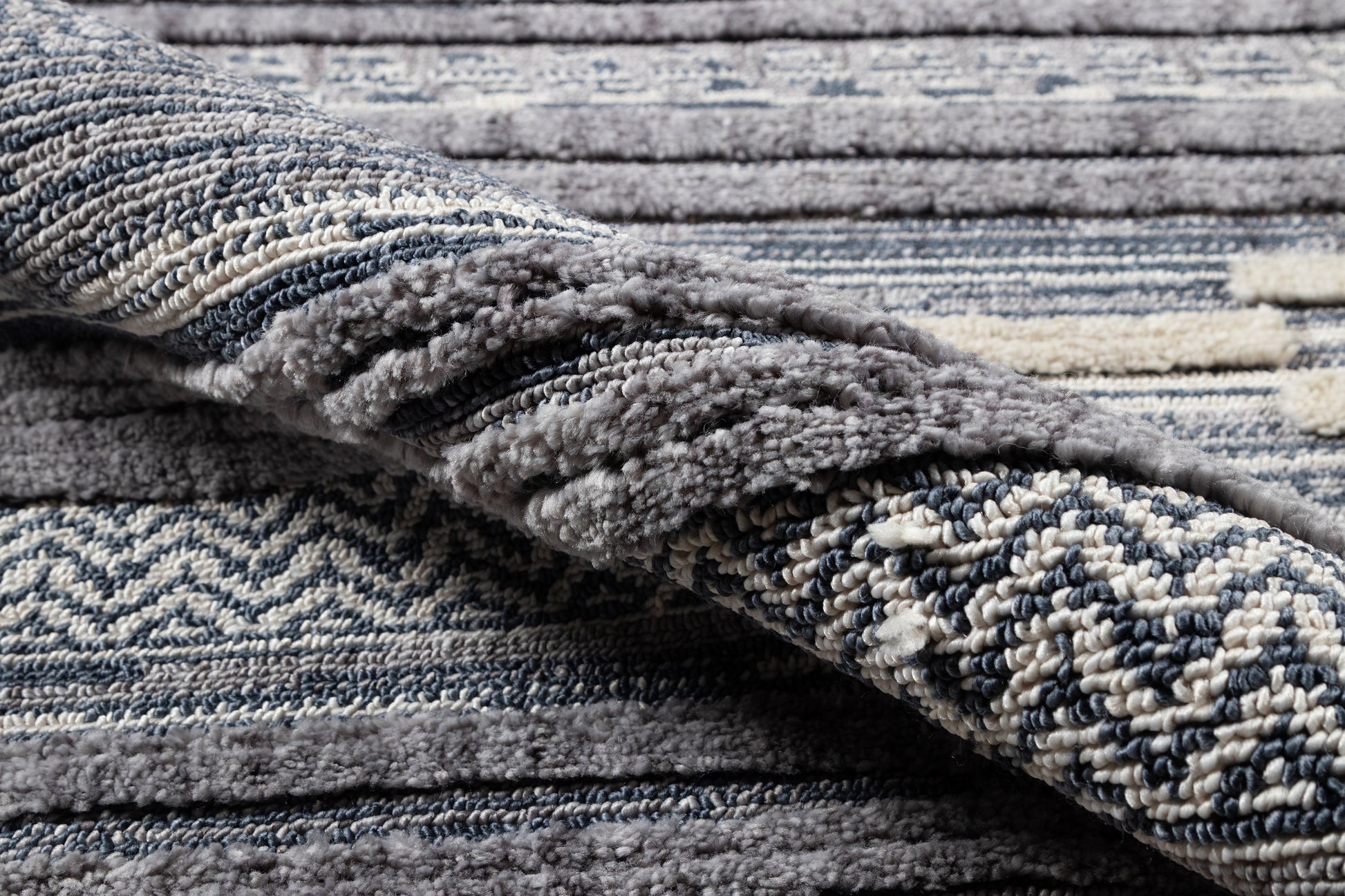 Blue-gray shag rug with ivory & navy chevron pattern, plush pile, folded edge.
