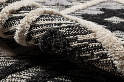 Close-up of black & ivory geometric woven rug with plush beige fringe.