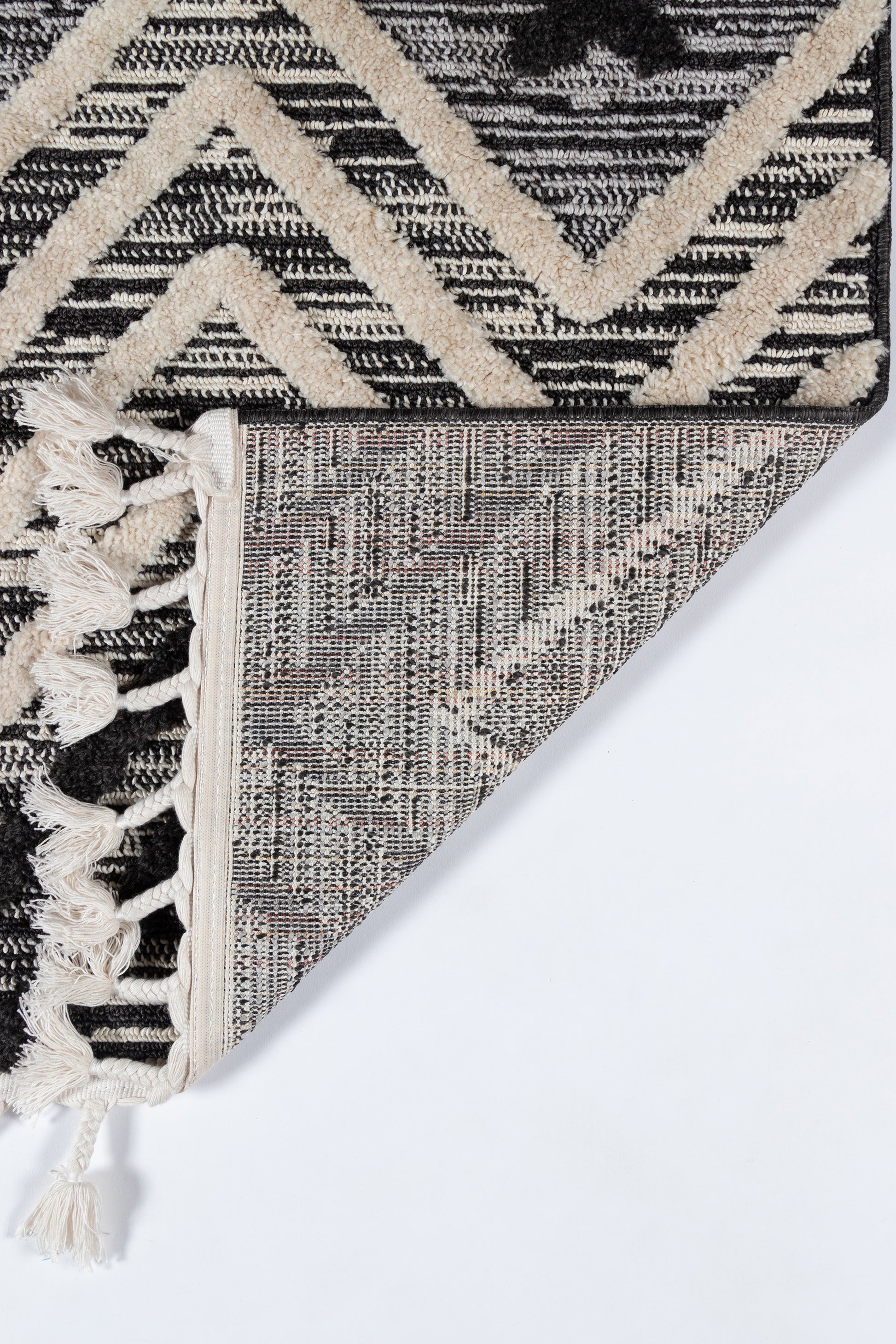 Black and ivory geometric rug with bold chevron pattern, knotted fringe, reversible woven backing.