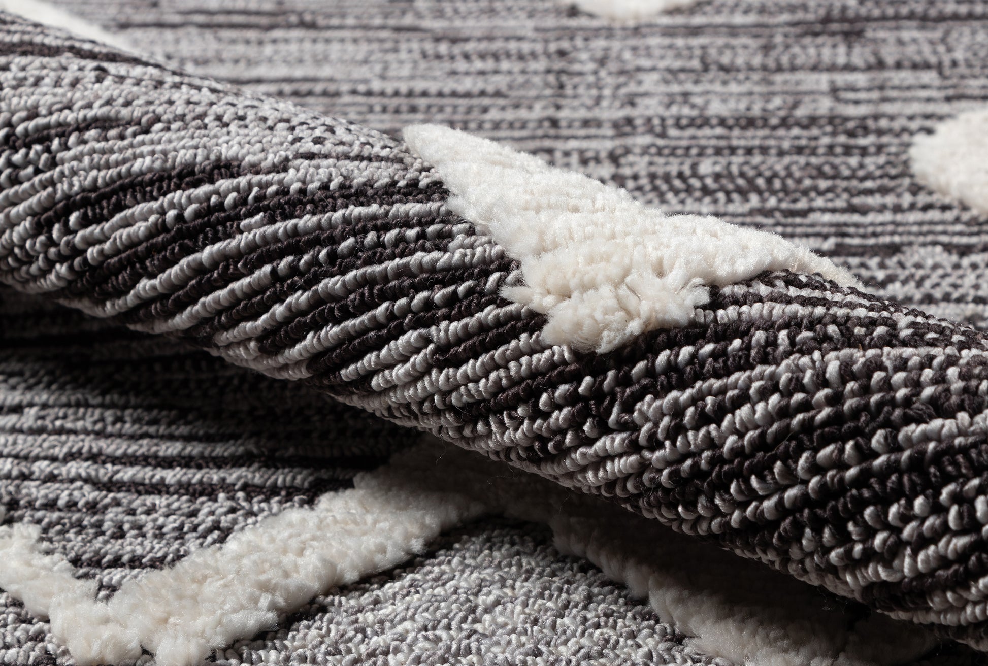 Close-up of a gray textured rug with dense looped pile and white sherpa backing.