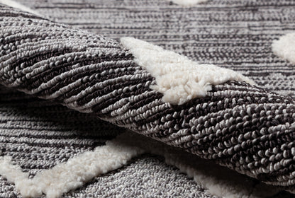 Close-up of a gray textured rug with dense looped pile and white sherpa backing.