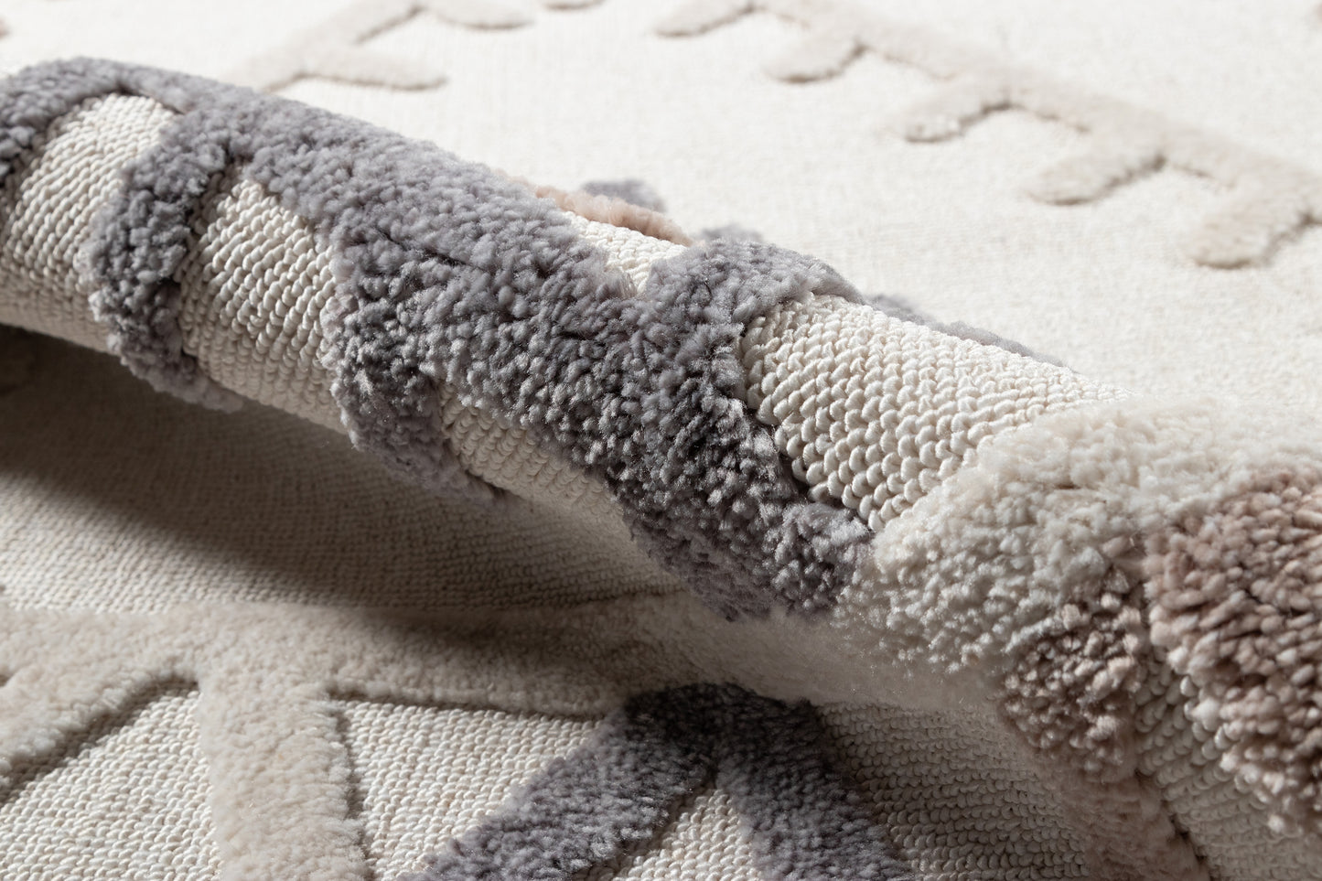 Neutral ivory and gray rug with plush boucle texture and rolled edge, cozy modern decor.