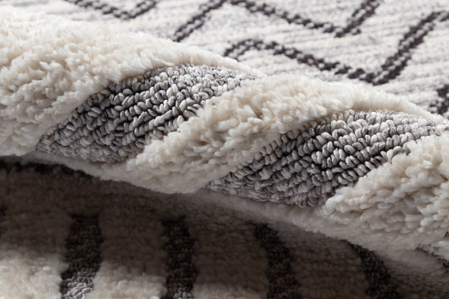 Ivory & gray plush shag rug with chunky pile & striped pattern, folded to show soft, cozy texture.