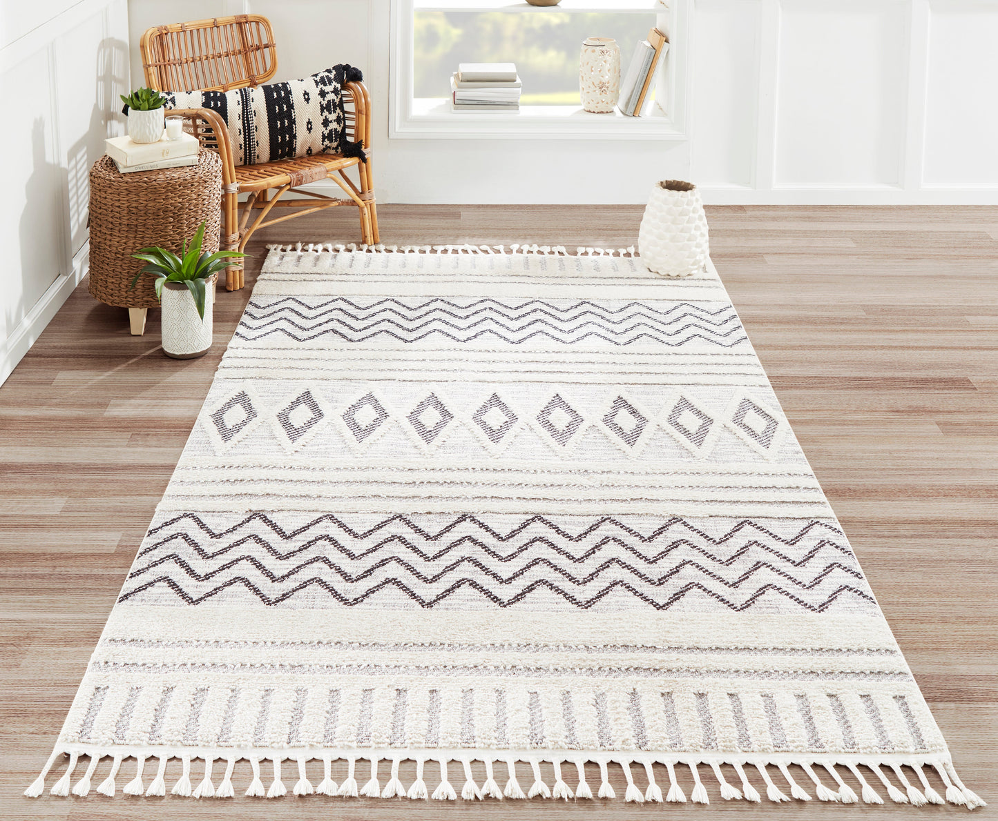 Rectangular ivory-and-gray woven rug with geometric diamonds and chevrons, fringe tassels; boho living room decor.