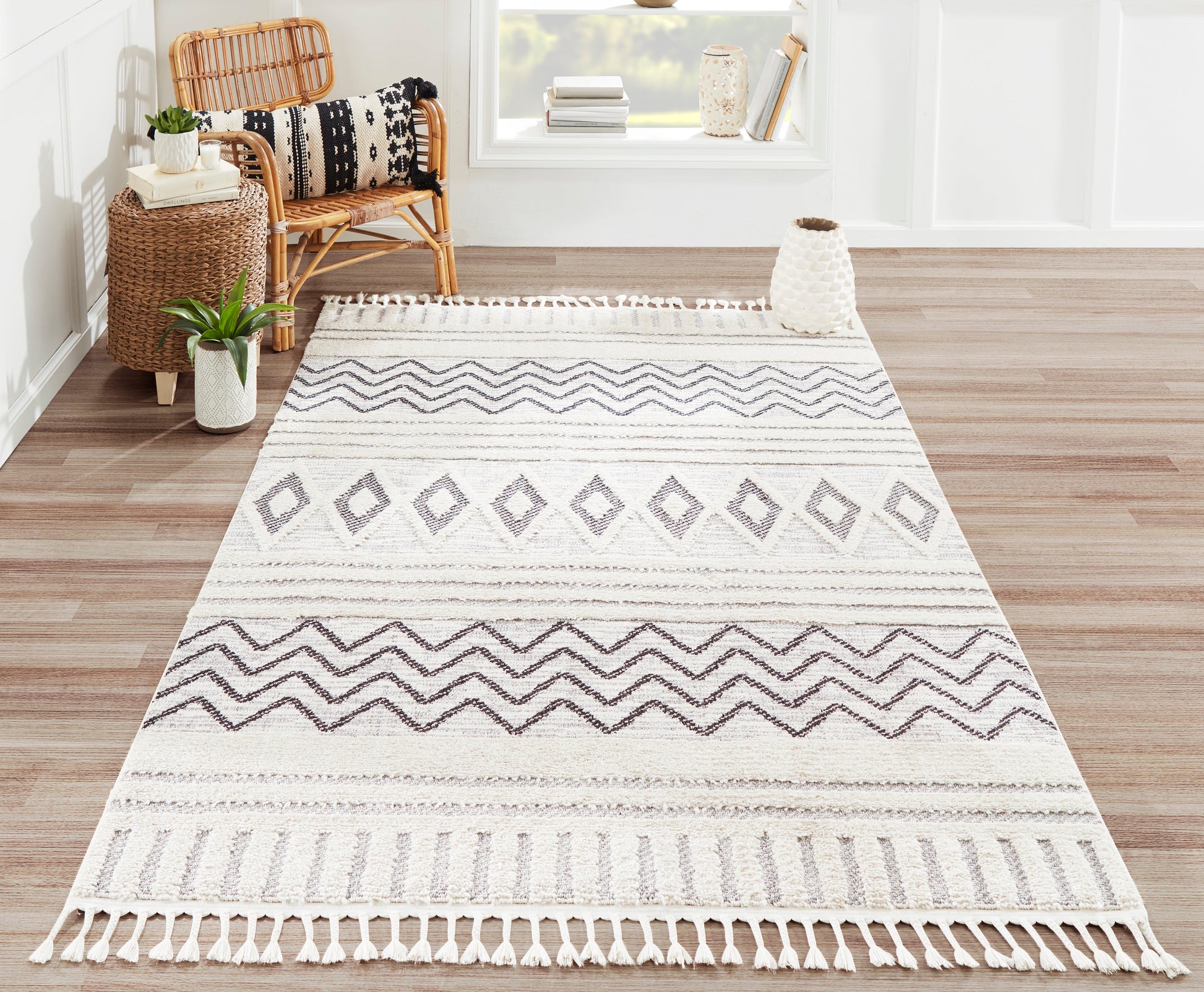 Rectangular ivory-and-gray woven rug with geometric diamonds and chevrons, fringe tassels; boho living room decor.