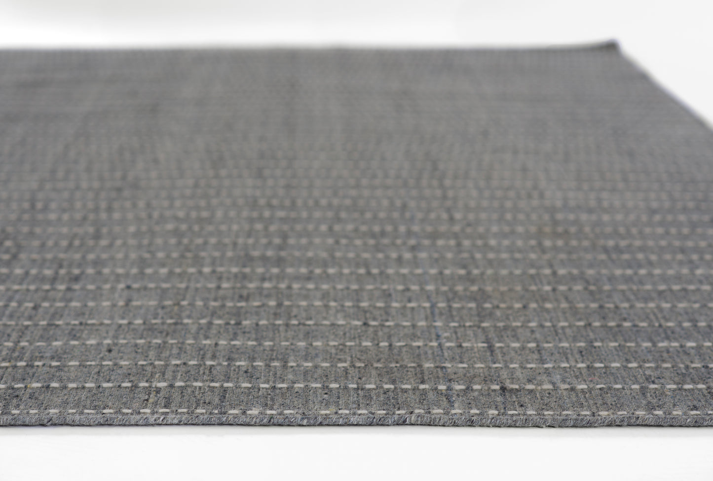 Dark gray woven rug with a light gray dotted grid pattern; rectangular, modern textile.