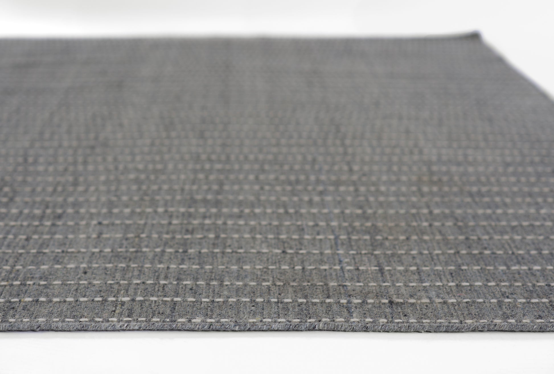 Dark gray woven rug with a light gray dotted grid pattern; rectangular, modern textile.