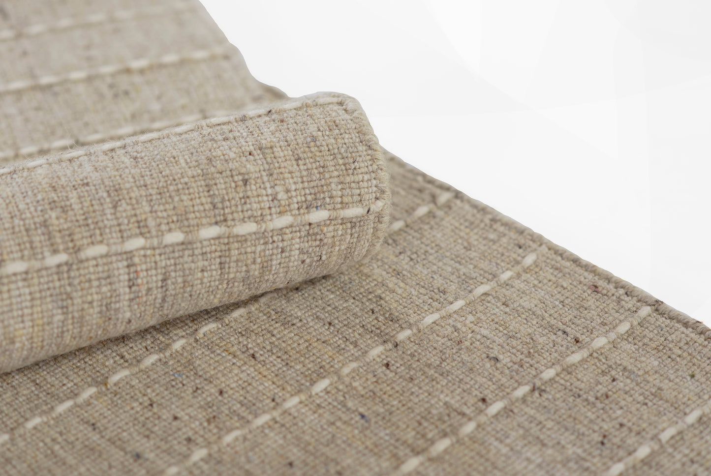 Natural beige jute rug with woven flatweave texture, white stitched edges, rolled corner detail.