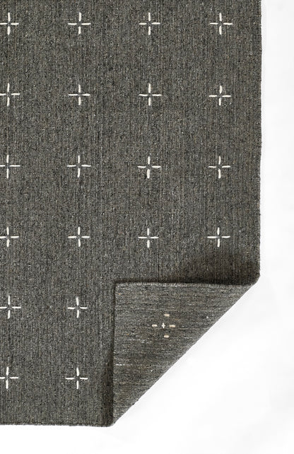 Charcoal gray woven rug with white plus-sign grid pattern; textured fabric with folded corner.