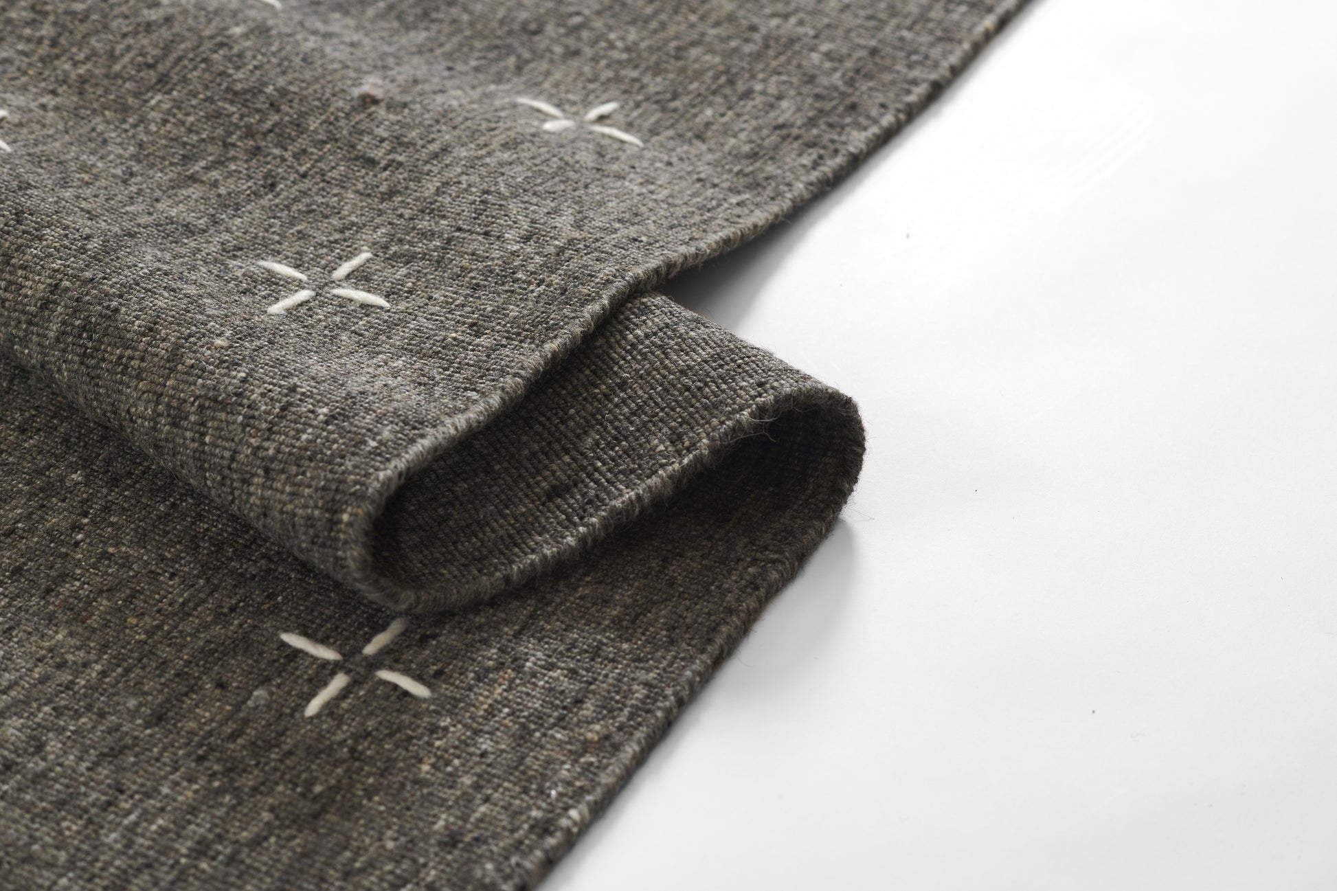 Olive-toned woven rug with subtle cross-stitch accents and textured surface, 3'6" x 5'6
