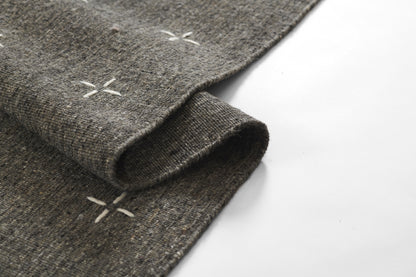 Olive-toned woven rug with subtle cross-stitch accents and textured surface, 3'6" x 5'6