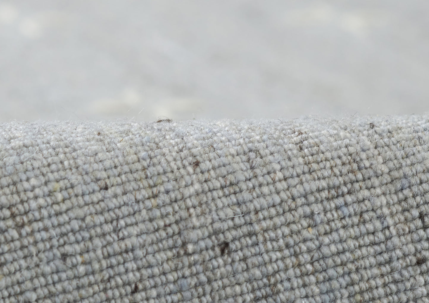 Close-up of gray woven rug fabric with boucle-like texture, soft and durable.