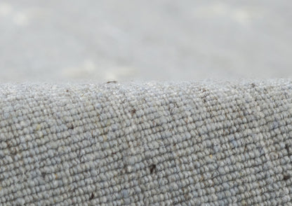 Close-up of gray woven rug fabric with boucle-like texture, soft and durable.