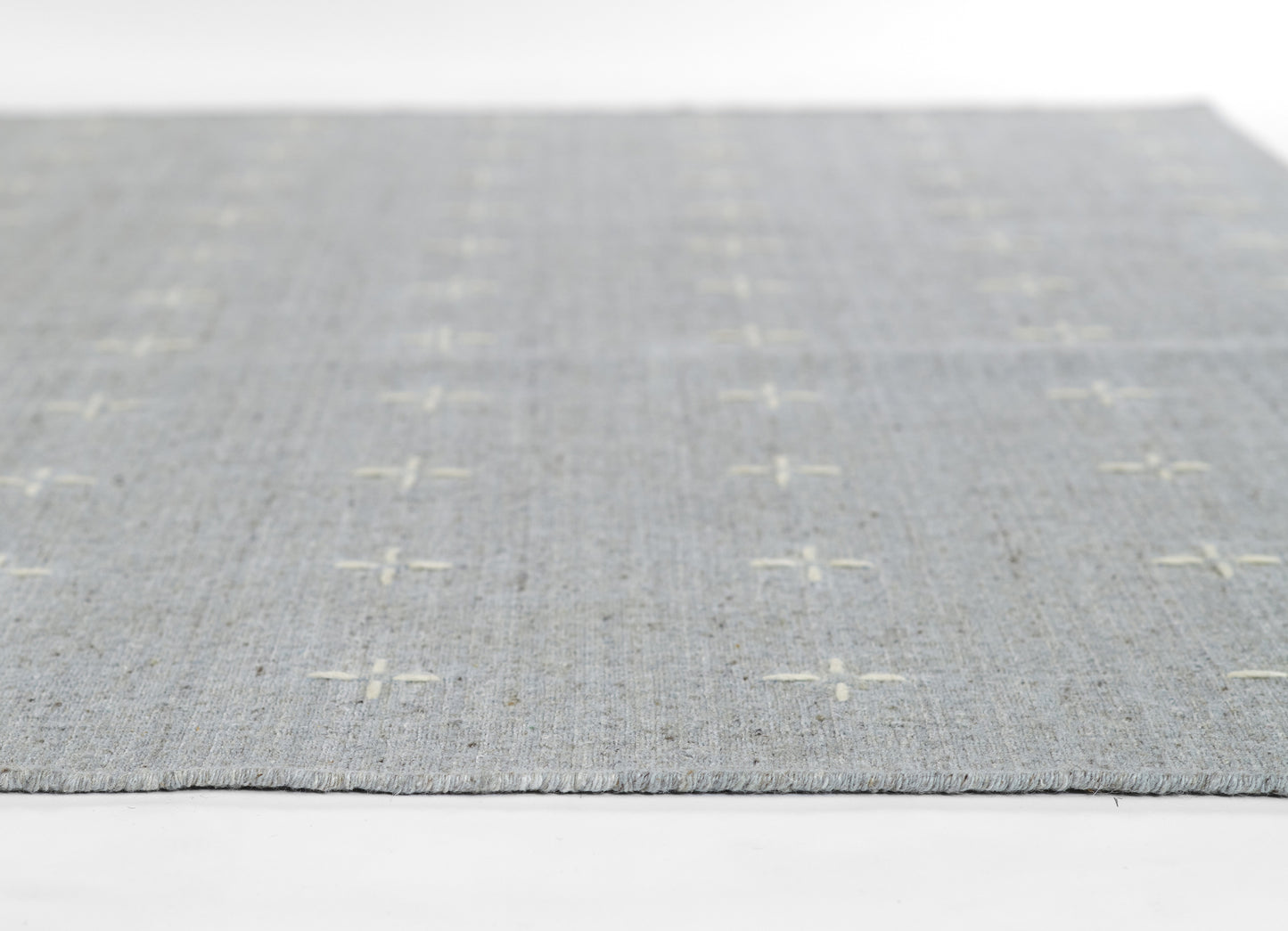 Light gray flatwoven rug with white plus-sign motifs, rectangular living-room rug.