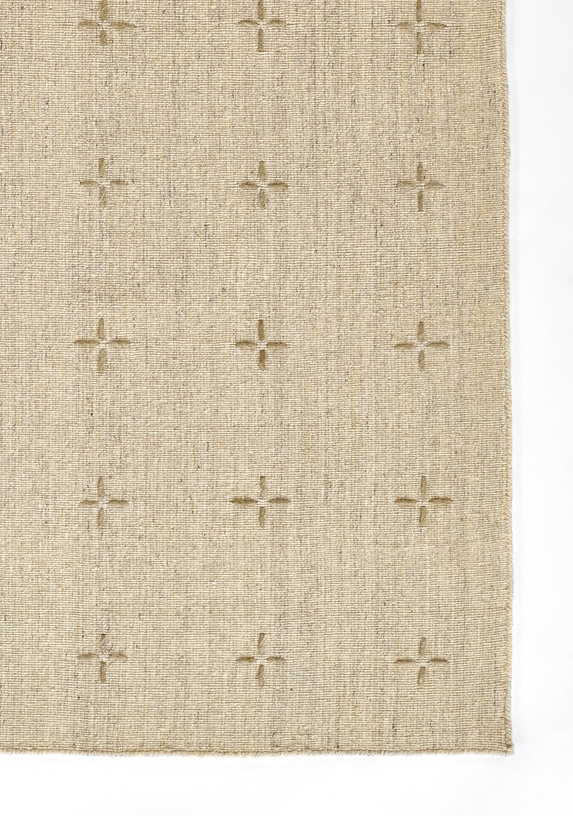 Beige woven rug with small cream cross motifs, textured linen-look fabric for neutral floor decor.