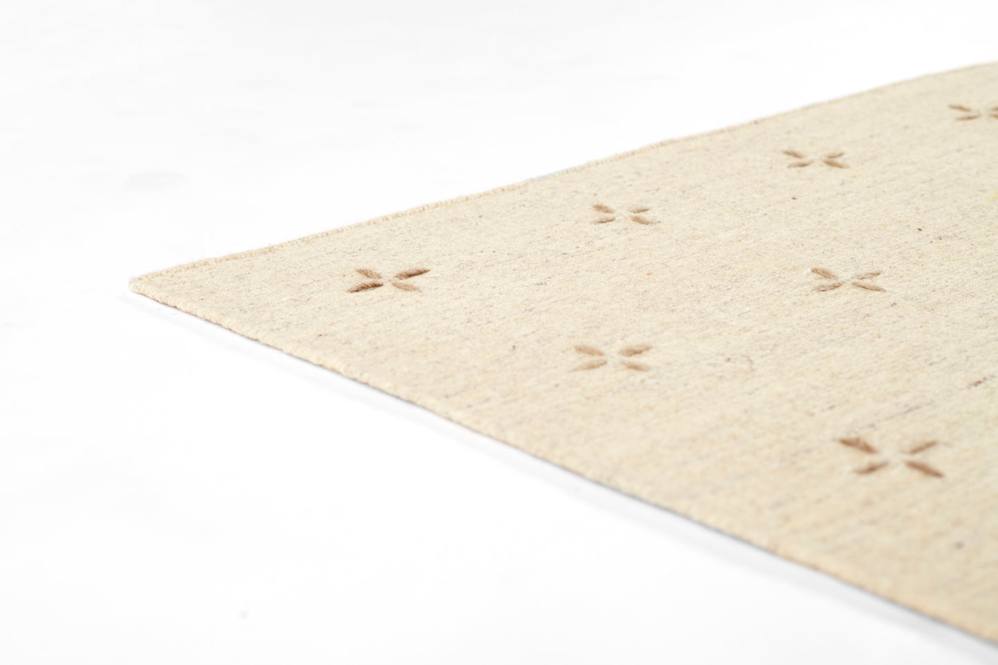 Beige natural jute rug with small cross-cutout motifs; rectangular, rustic rug.