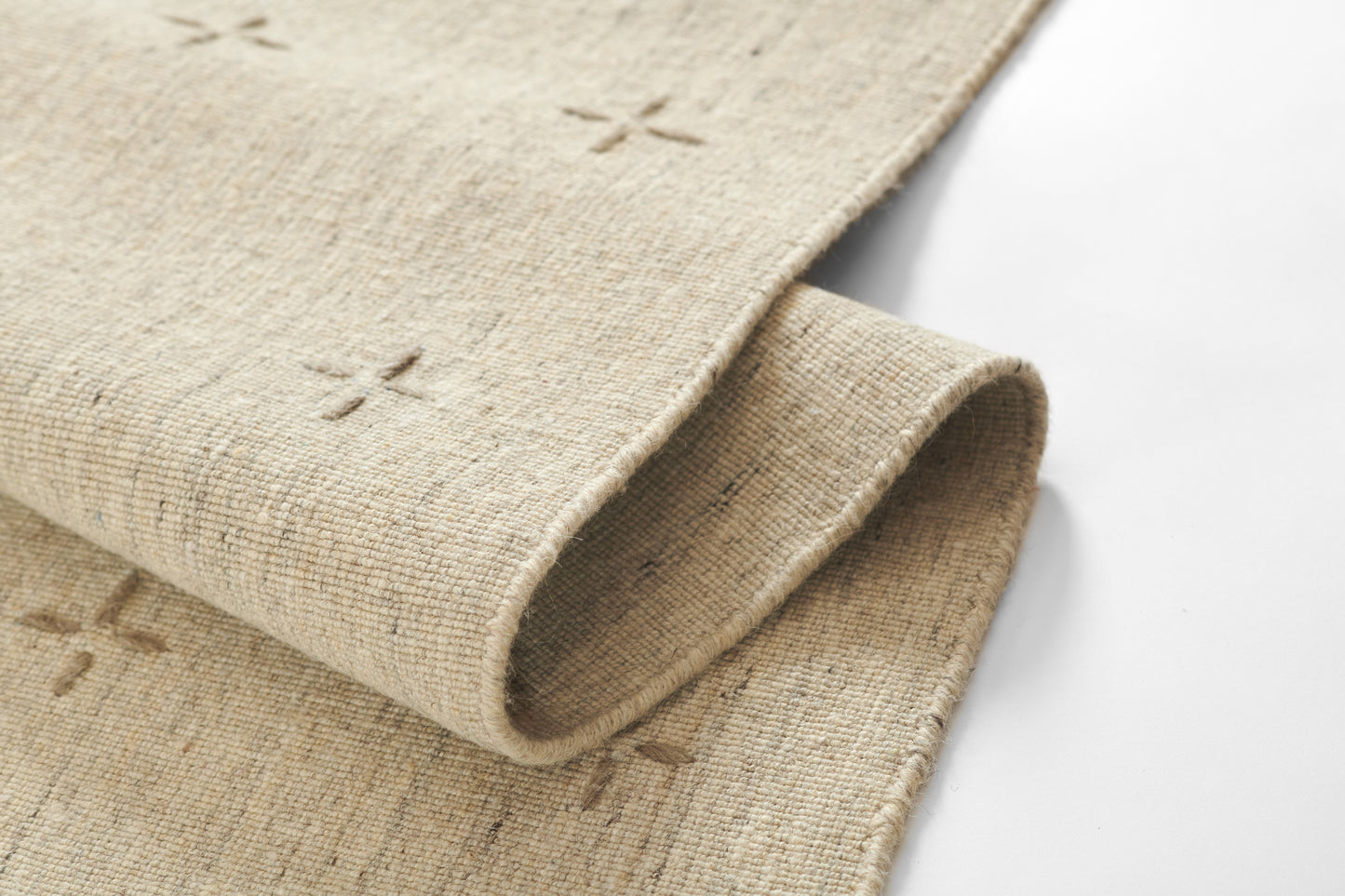 Natural beige woven rug with X cross-stitch motifs & rolled edge, rustic home decor.