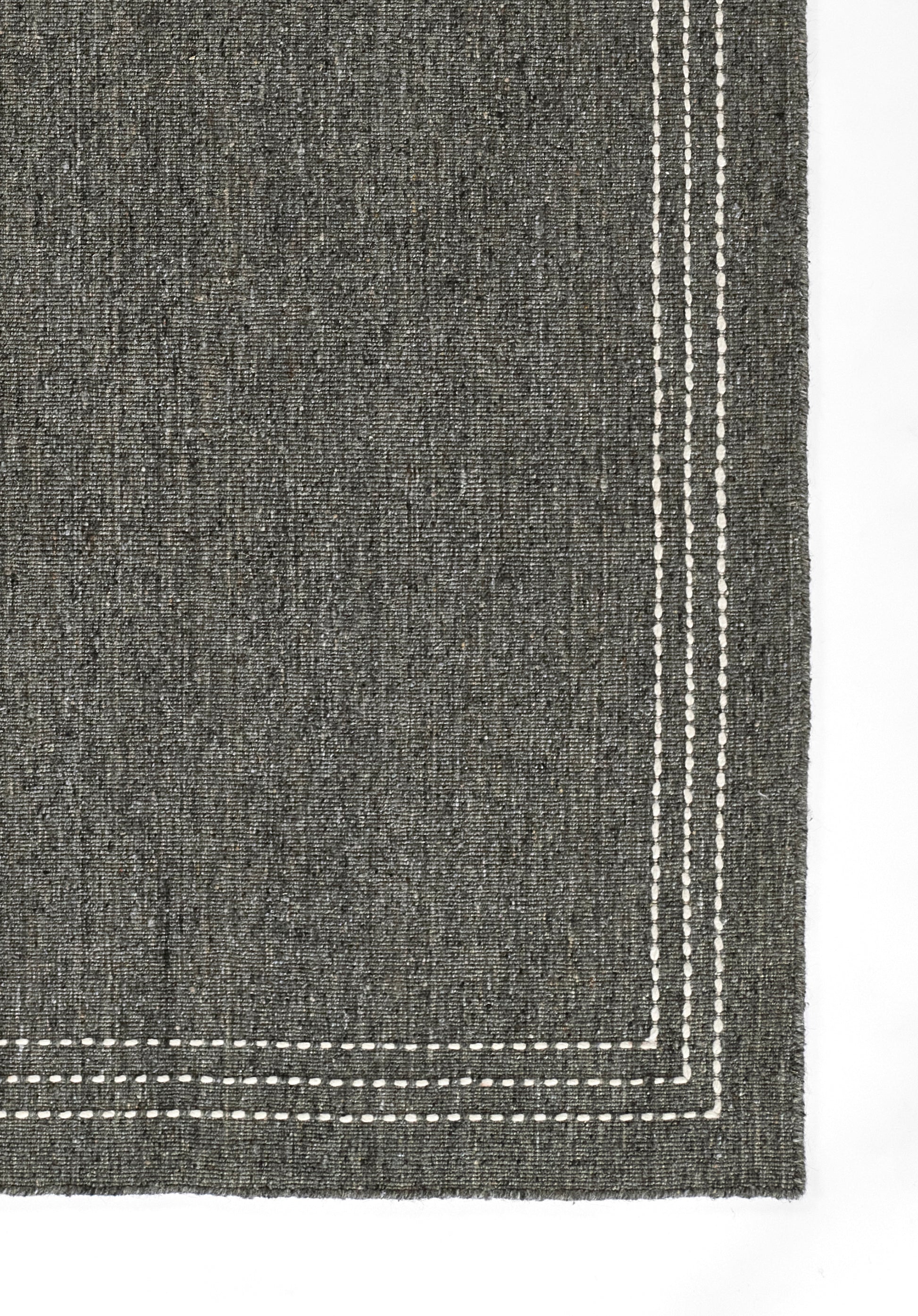 Charcoal gray woven rug with white dashed border stitching along the edges.