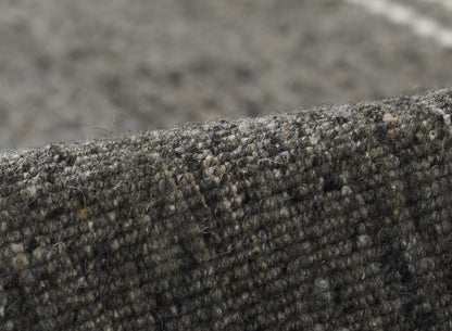 Close-up of olive, grey & black boucle tweed rug with a wooly, textured finish.