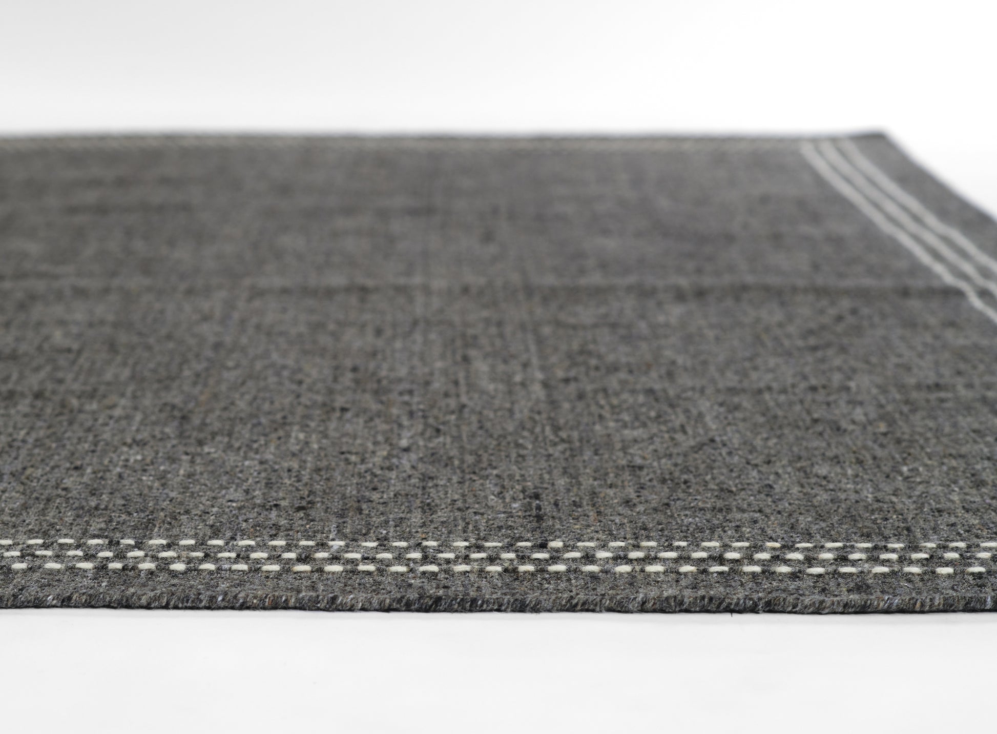 Olive color flat-weave rug with white stitched border, textured surface, rectangular, modern minimalist style.