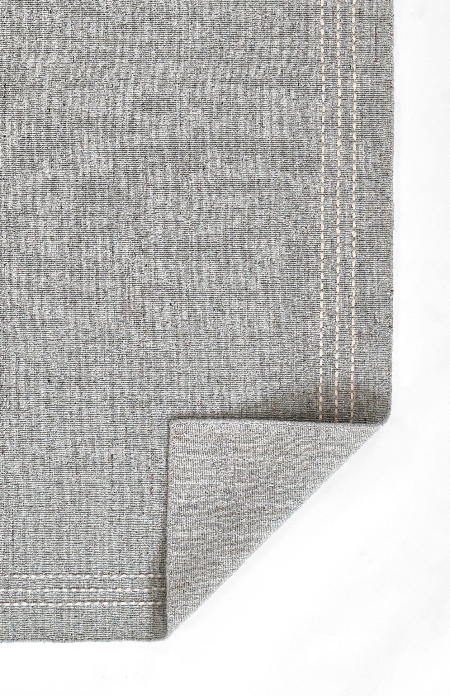 Grey linen placemat with double white top-stitch border and folded corner.