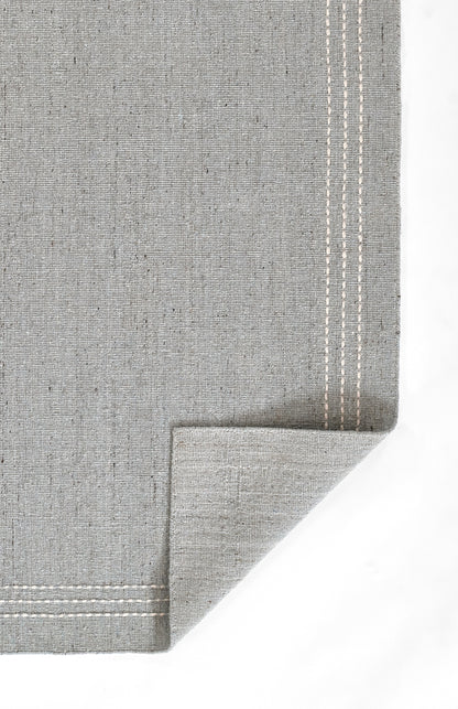 Grey linen placemat with double white top-stitch border and folded corner.