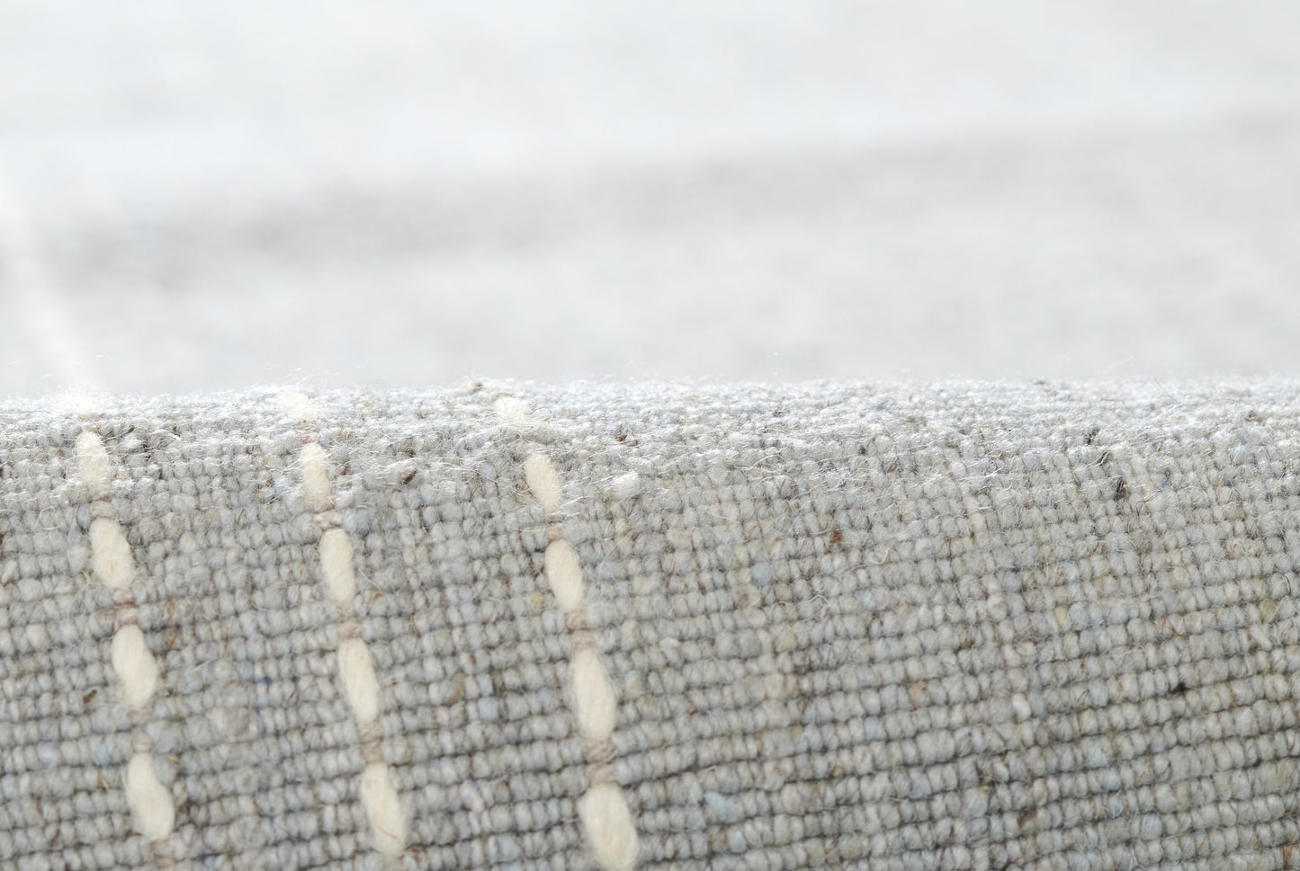 Rolled gray woven runner rug with cream vertical dashed lines; textured, modern home decor.
