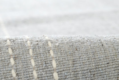 Close-up of grey woven fabric with cream vertical stitch lines; textured upholstery or rug material.