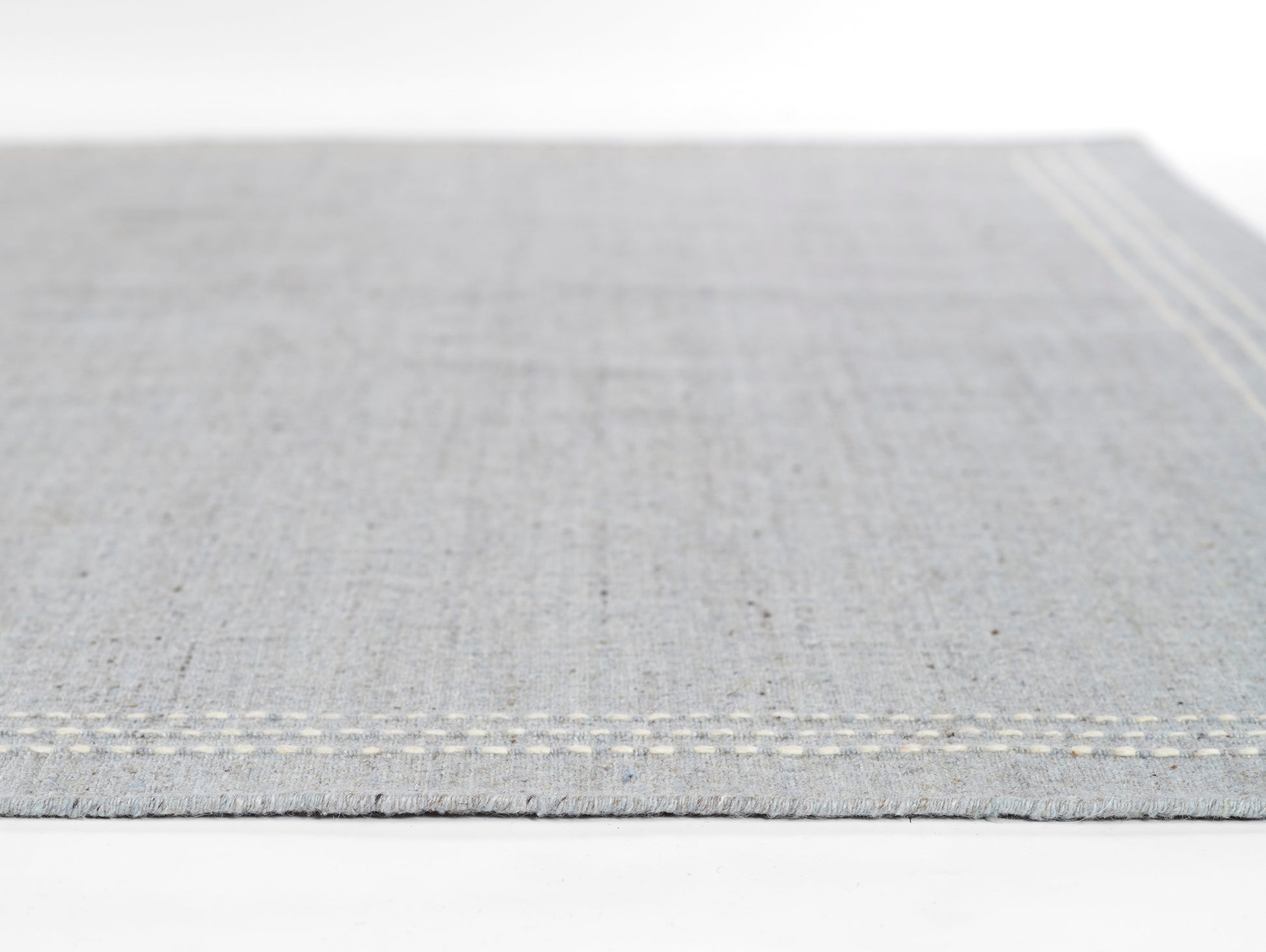 Light gray rug with a double white stitch border; rectangular area rug.