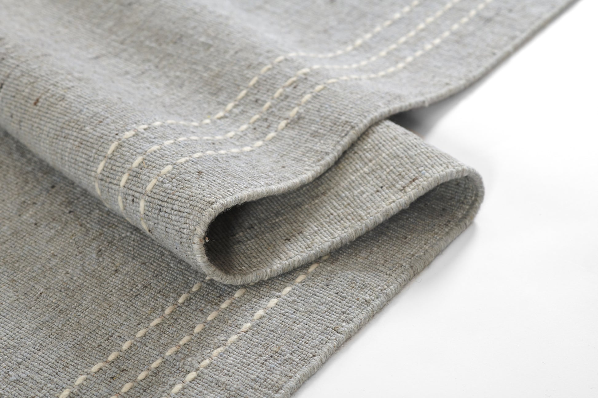Gray linen tea towel with white topstitching along a stitched border, folded for rustic kitchen use.