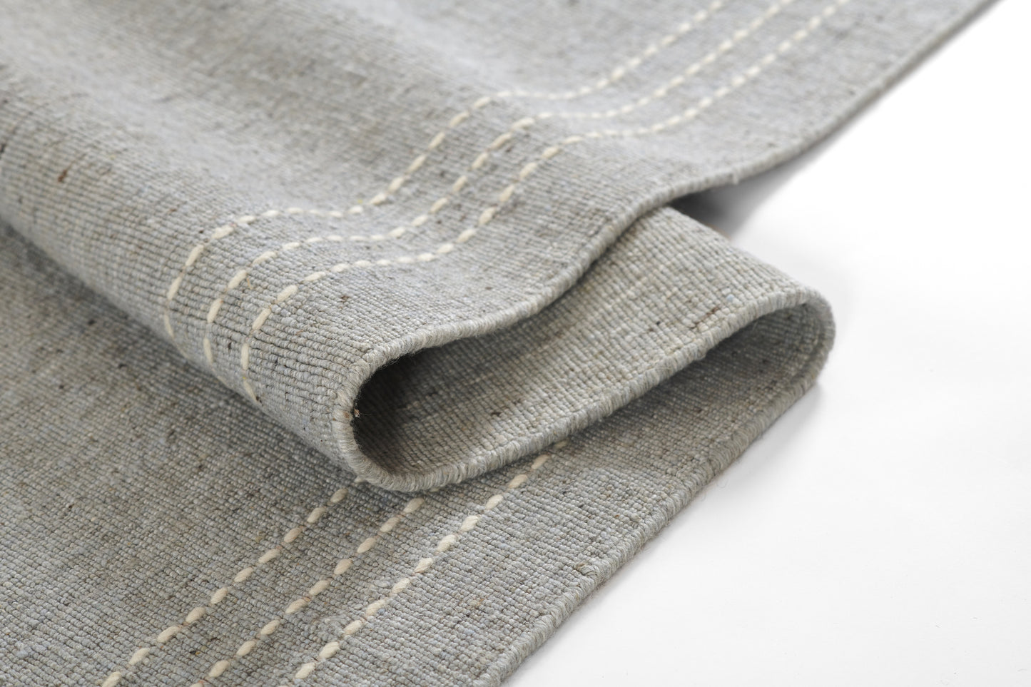 Gray rug with white stitched stripes along the edge.