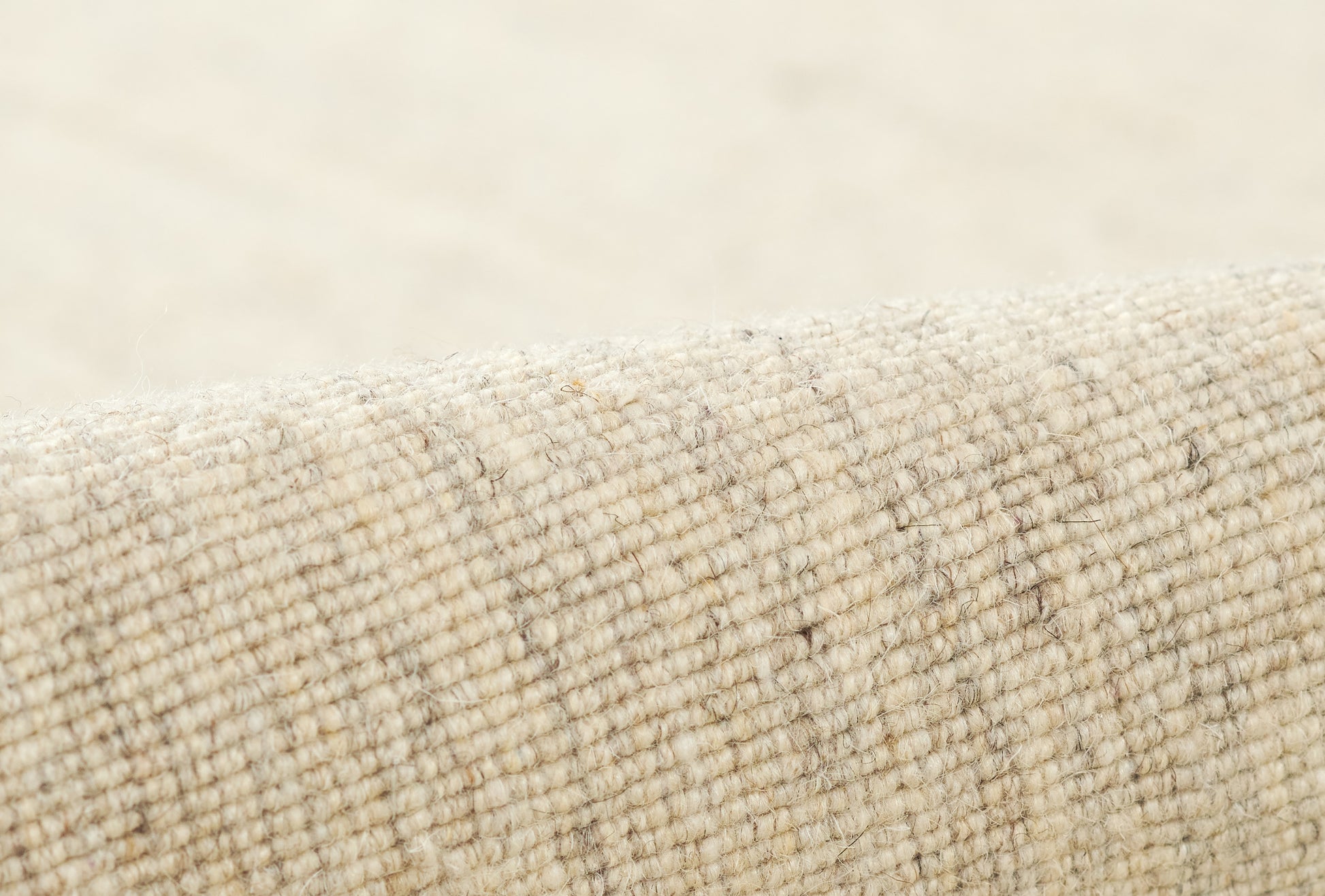 Beige natural wool rug close-up with a textured loop weave and subtle plaid lines; cozy rug texture.