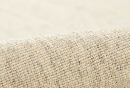 Beige natural wool rug close-up with a textured loop weave and subtle plaid lines; cozy rug texture.