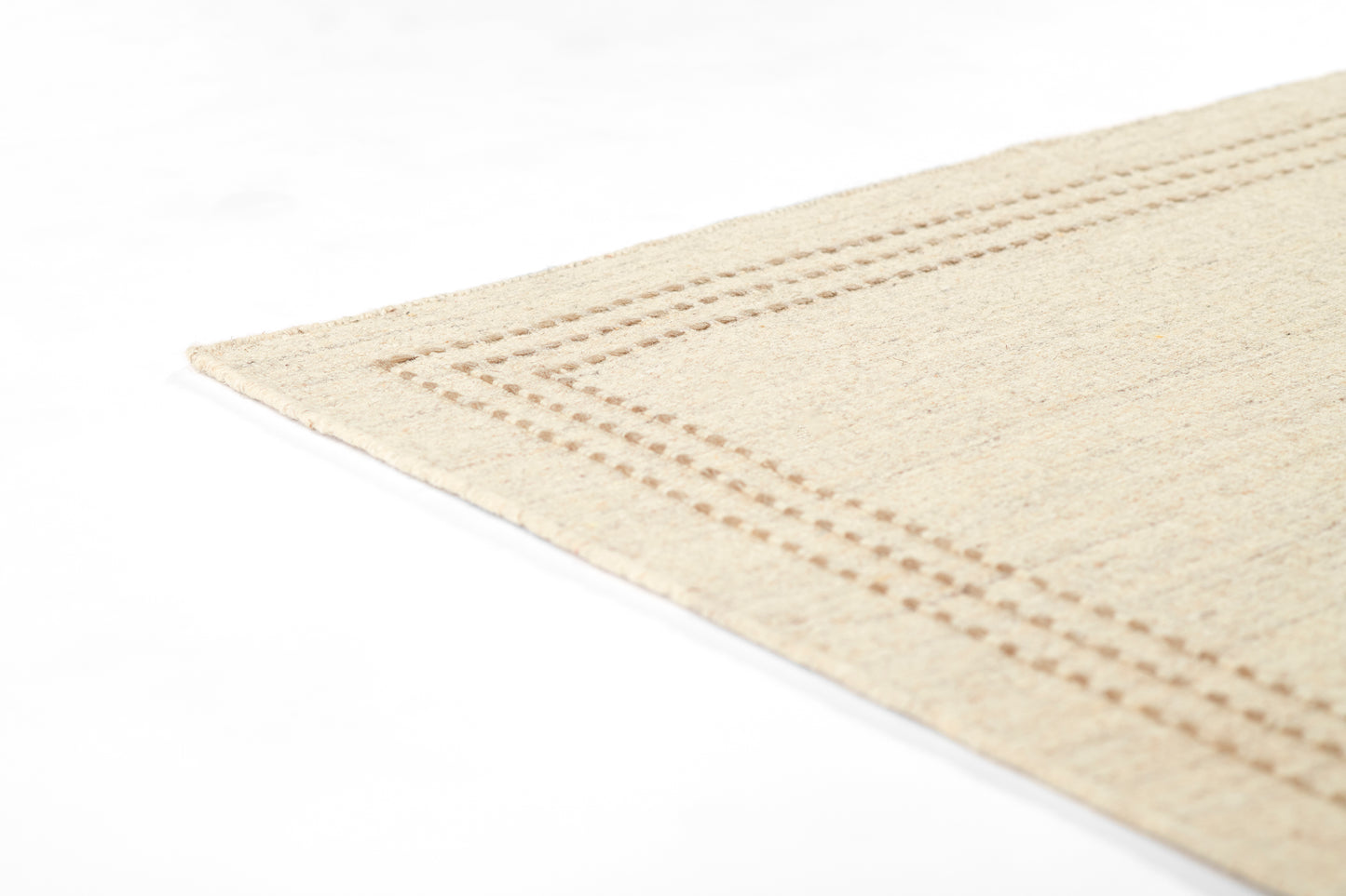 Beige woven rug with a dotted stitched border, close-up corner view.