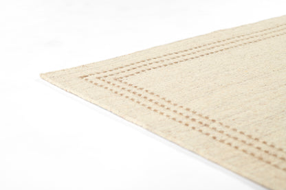 Beige natural-fiber rug with dotted stitched border along edge, corner view.
